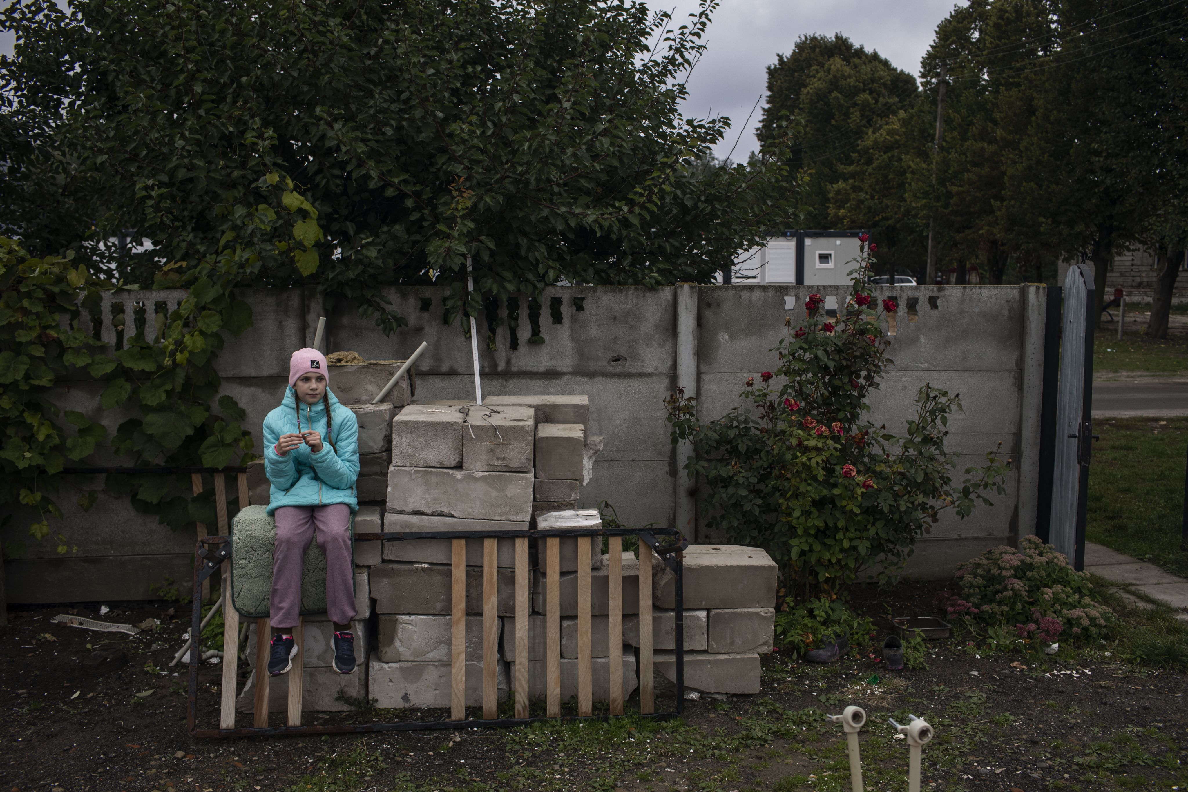 Veronika sits on a pile of concrete blocks near the family's destroyed home.