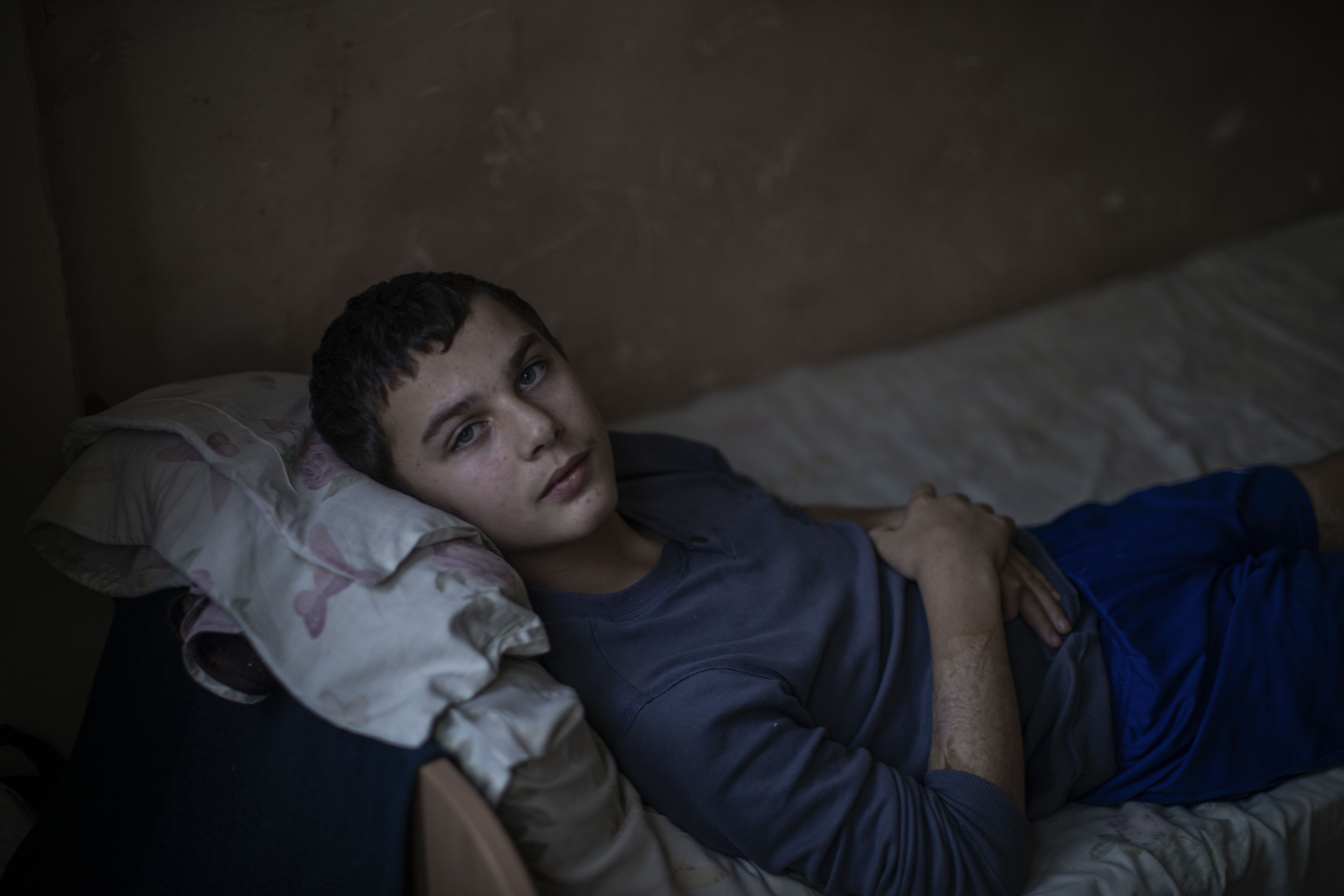Mykhailo lays on a bed in a hospital.