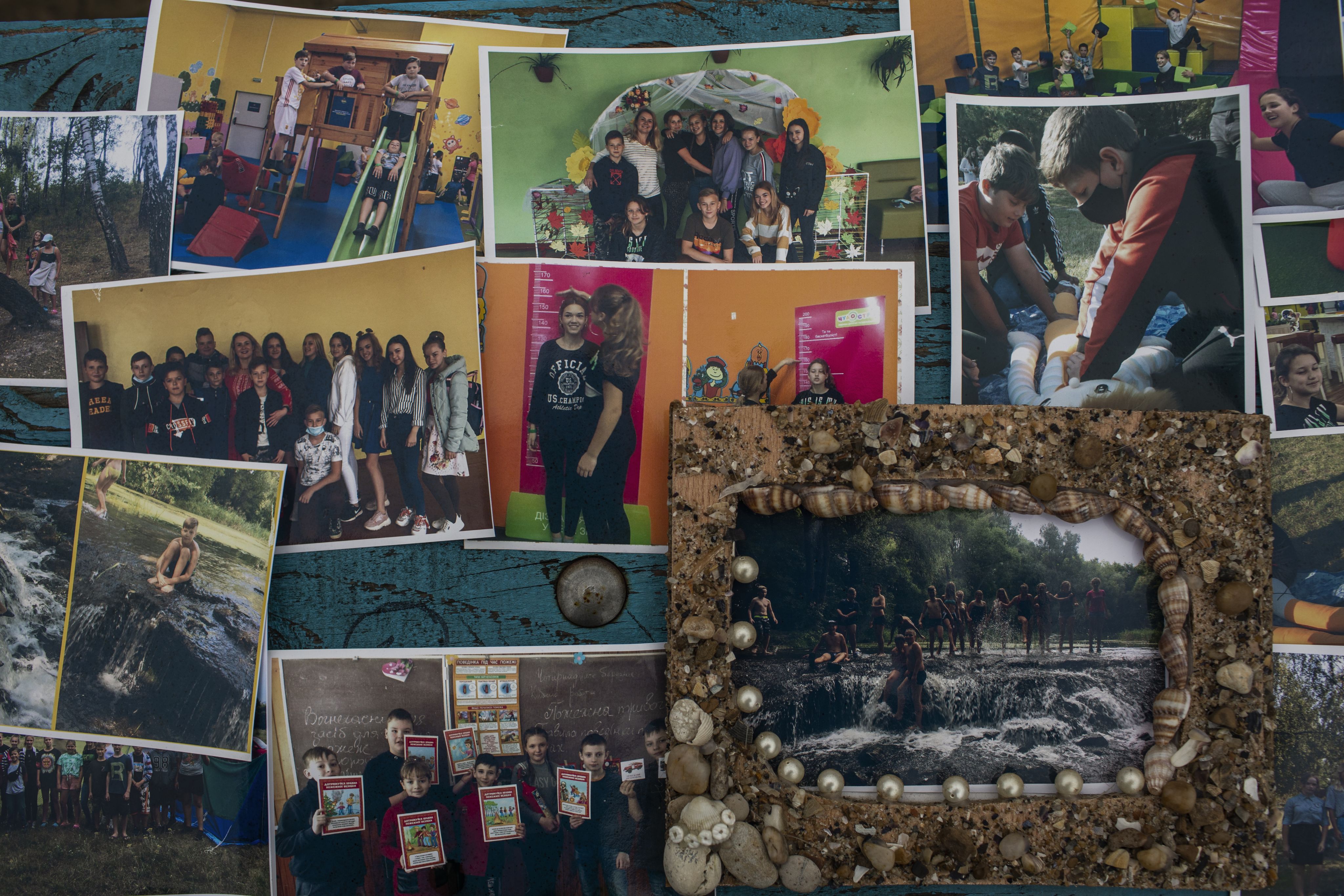 A collage of photos of children taken before the war is displayed on a wall.