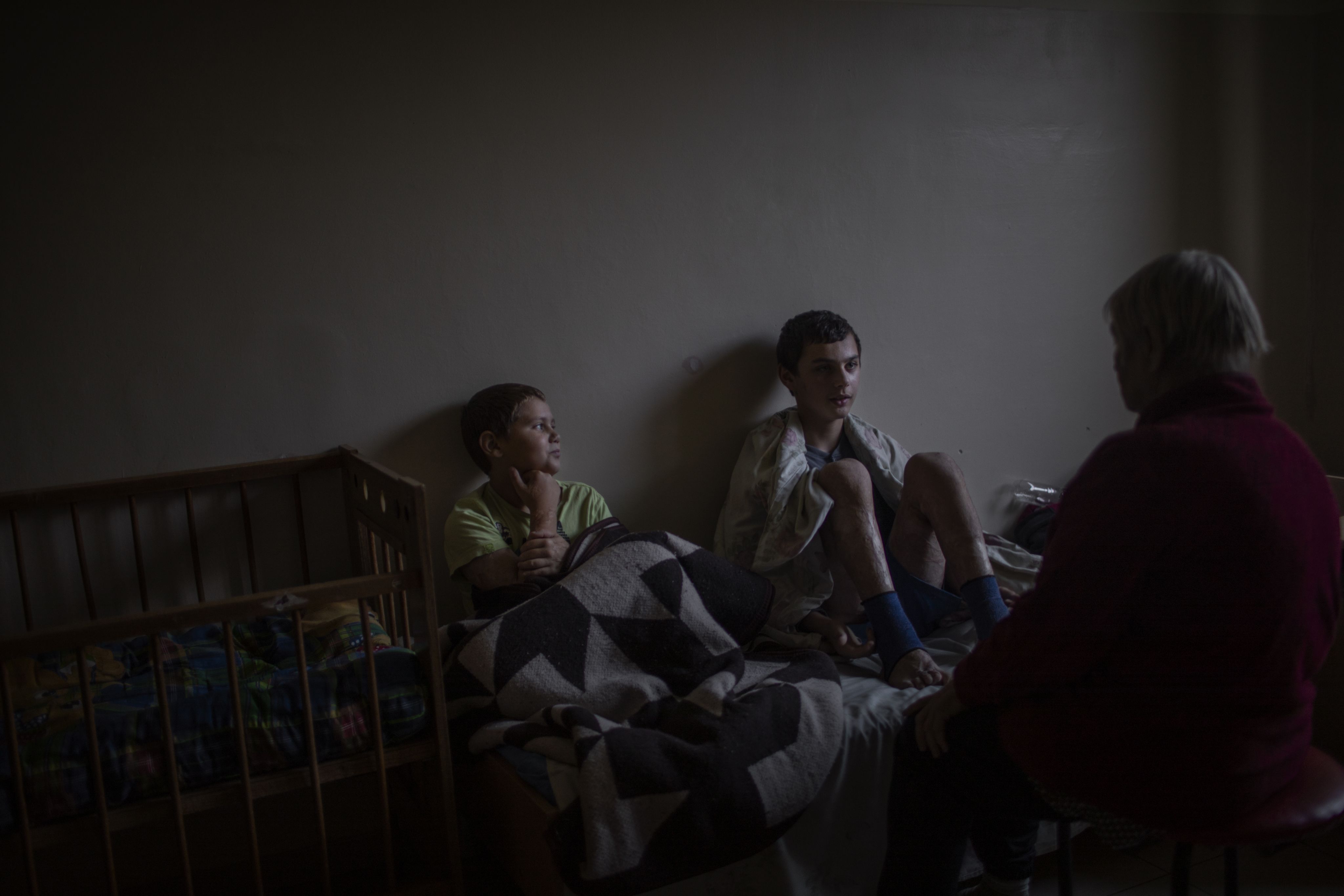 Mykhailo sits next to his brother on a bed at the hospital.